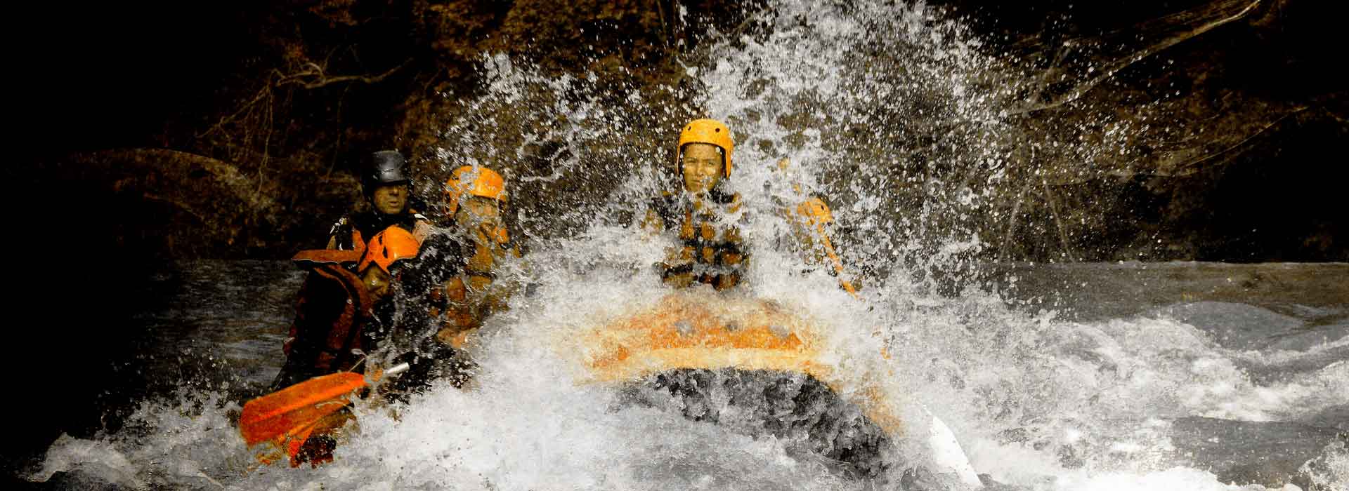 Gros plan d'un raft avec client dans les rapides, ça éclabousse un max